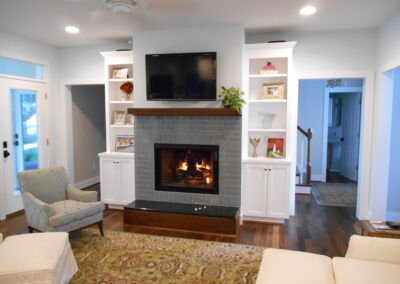 new gas fireplace in living room with stone surround and wooden mantel