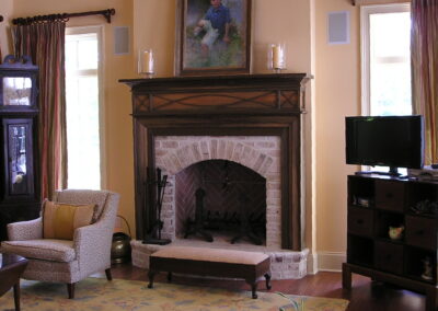 new gas fireplace in living room with white stone surround and wooden mantel