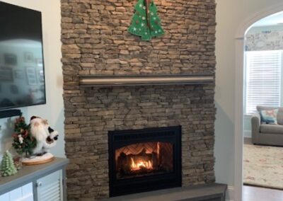 new gas fireplace in living room with stone surround