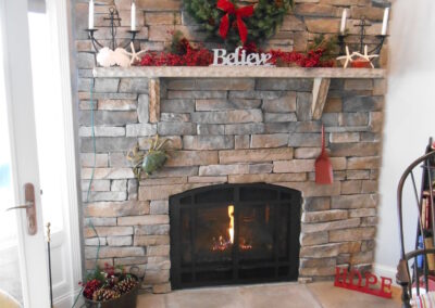new gas fireplace in living room with stone surround and white mantel