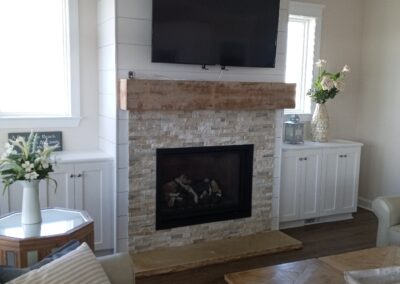 new gas fireplace in living room with light brick surround and light wood mantel